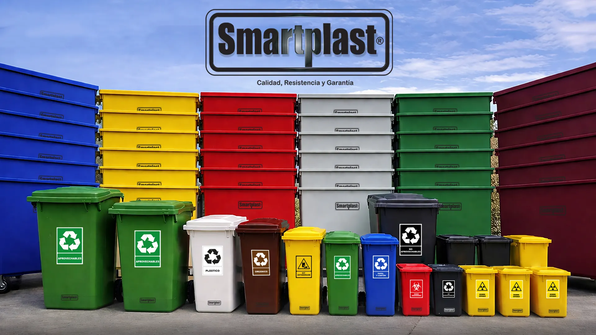 Vista panorámica de una exhibición de productos Smartplast que muestra una amplia gama de contenedores de polietileno para gestión de residuos. Incluye grandes dumpsters con ruedas apilados y una fila de papeleras de reciclaje codificadas por color (azul, amarillo, rojo, gris, verde, marrón, blanco) con símbolos de reciclaje claros, bajo un cielo azul parcial. Perfecto para soluciones de separación de residuos comerciales, industriales y urbanos.